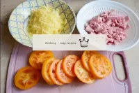 沸騰したソーセージを小さく切る。チーズをすりおろして。トマトを0。5 cmほどの厚さの円に切ります。...