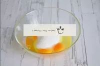 將雞蛋砸成一個單獨的碗，然後用糖攪拌到郁郁蔥蔥的淺色質量。...