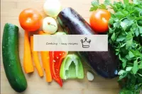 流水の下で野菜を洗います。courgetteとaubergineから果物をカットし、ピーマンで同じこ...