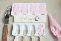 Insert the sticks into the popsicle moulds. Place ...