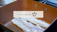 調理した魚のフィレ肉をオリーブオイルでストーブの上で加熱鍋で揚げる。...