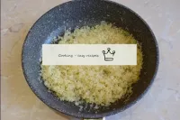 现在将蒸饭放入锅中搅拌。它浸泡在香油中。用小火炸米饭几分钟。大米会变透明，然后变金。...