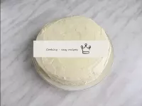 下のケーキにクリームのほとんどを塗り、2番目のケーキで覆い、軽く押します。ケーキの上部と側面を残りの...