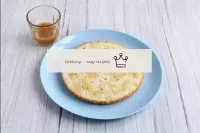Place the first cake on a flat plate, soak it in a...