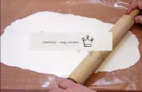 Cover the cutting board with cling film, evenly sp...