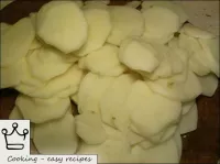 Batatas limpas são cortadas em queijo com canecas ...