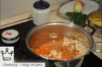 Drop roughly chopped carrots and other roots into ...